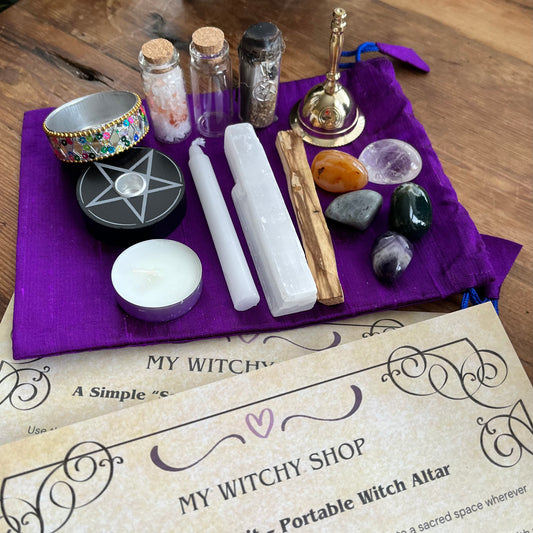 Witchy shop altar setup with candles, stones, and a pentacle symbol on a purple cloth.