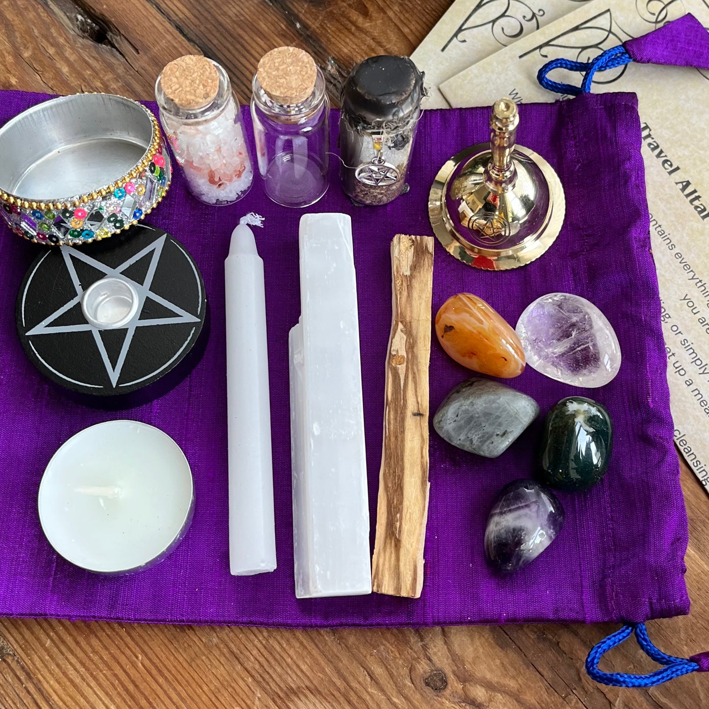Wiccan or pagan tools including candles, stones, and a pentacle on a purple cloth.