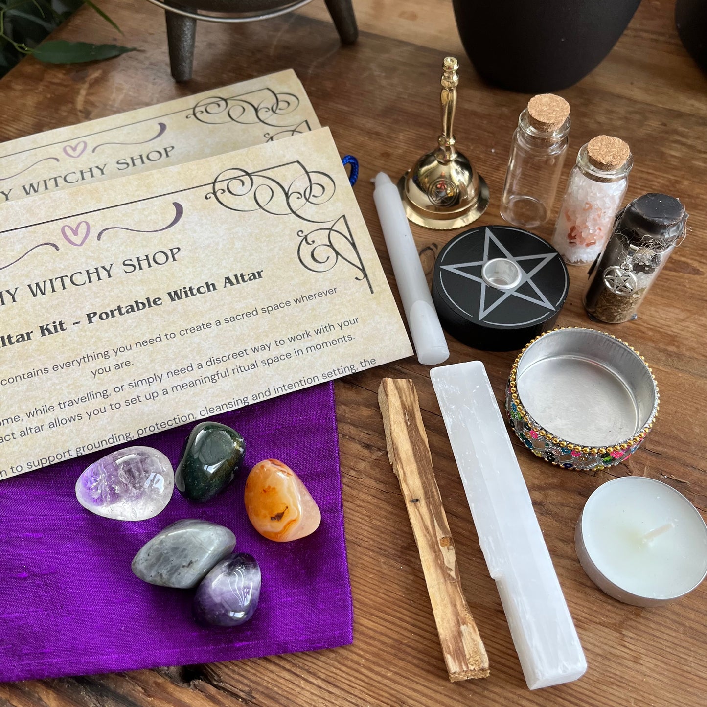 Witchy Shop portable altar kit with stones, candles, and other items on a wooden surface.