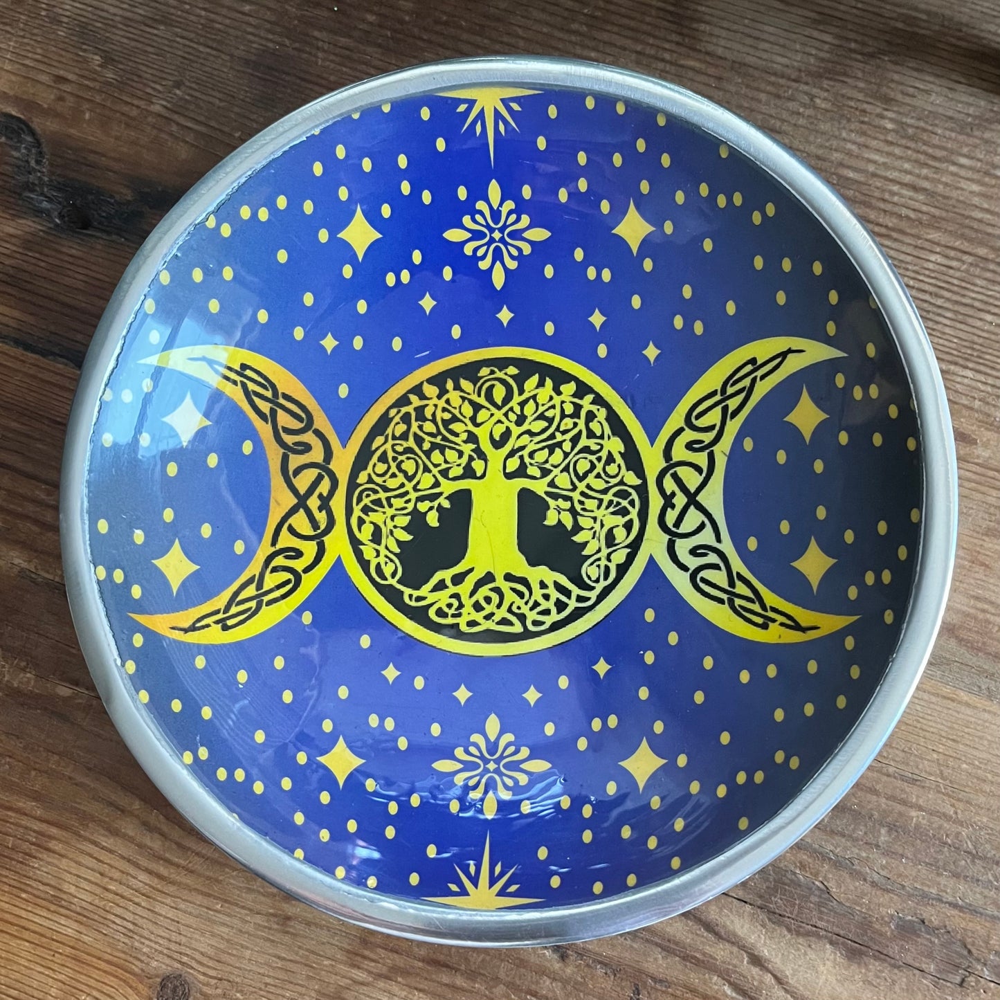 Decorative plate with tree of life and moon phases design on a blue background.