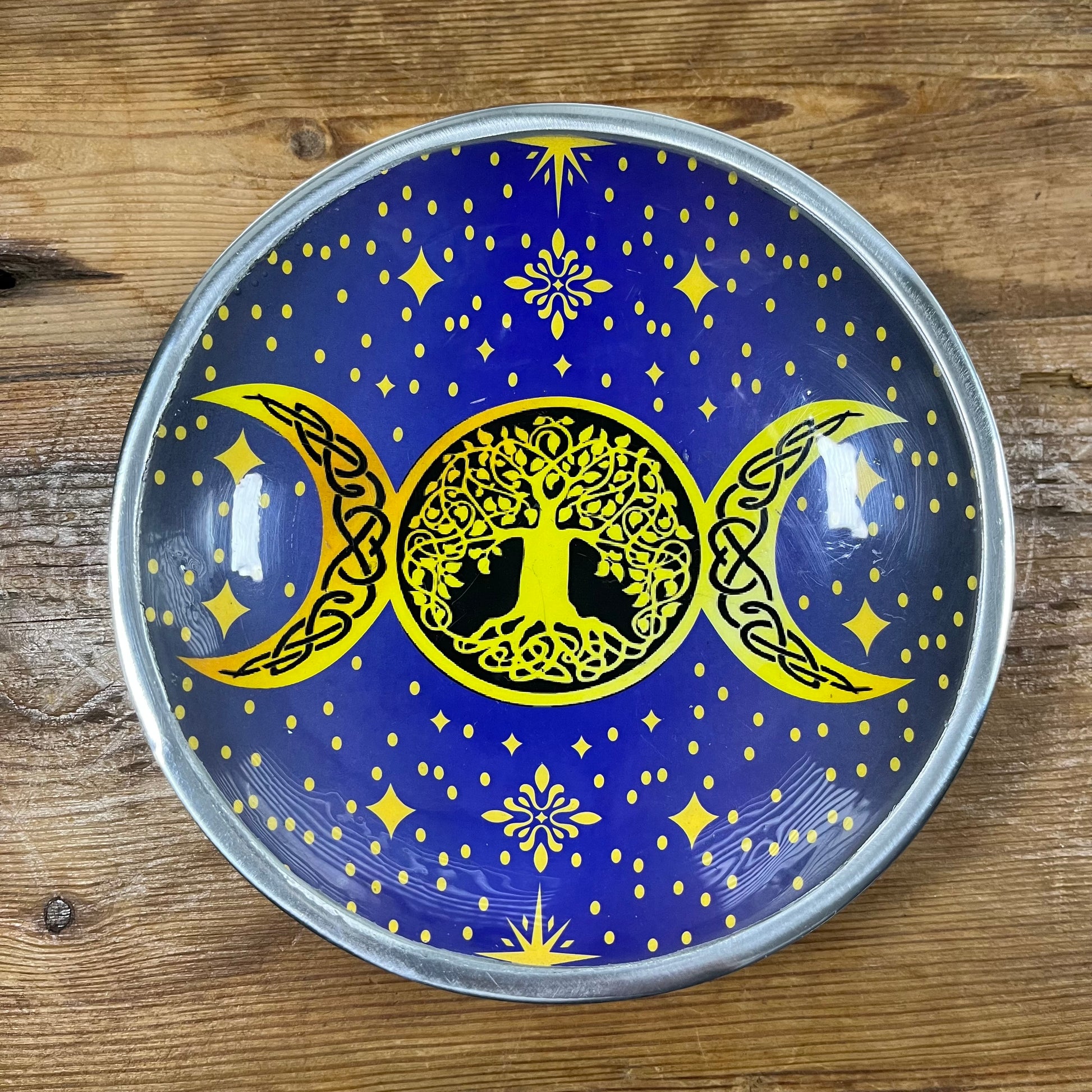 Decorative plate with tree of life design and celestial elements on a wooden surface