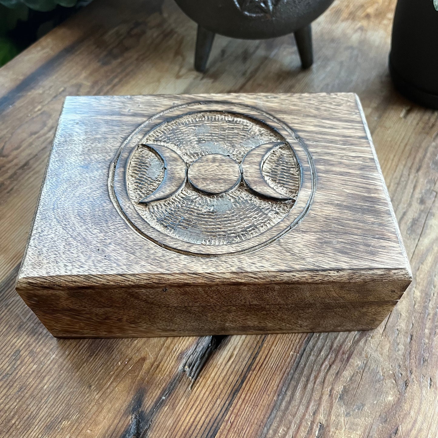 Wooden box with a engraved Triple moon symbol on a wooden surface