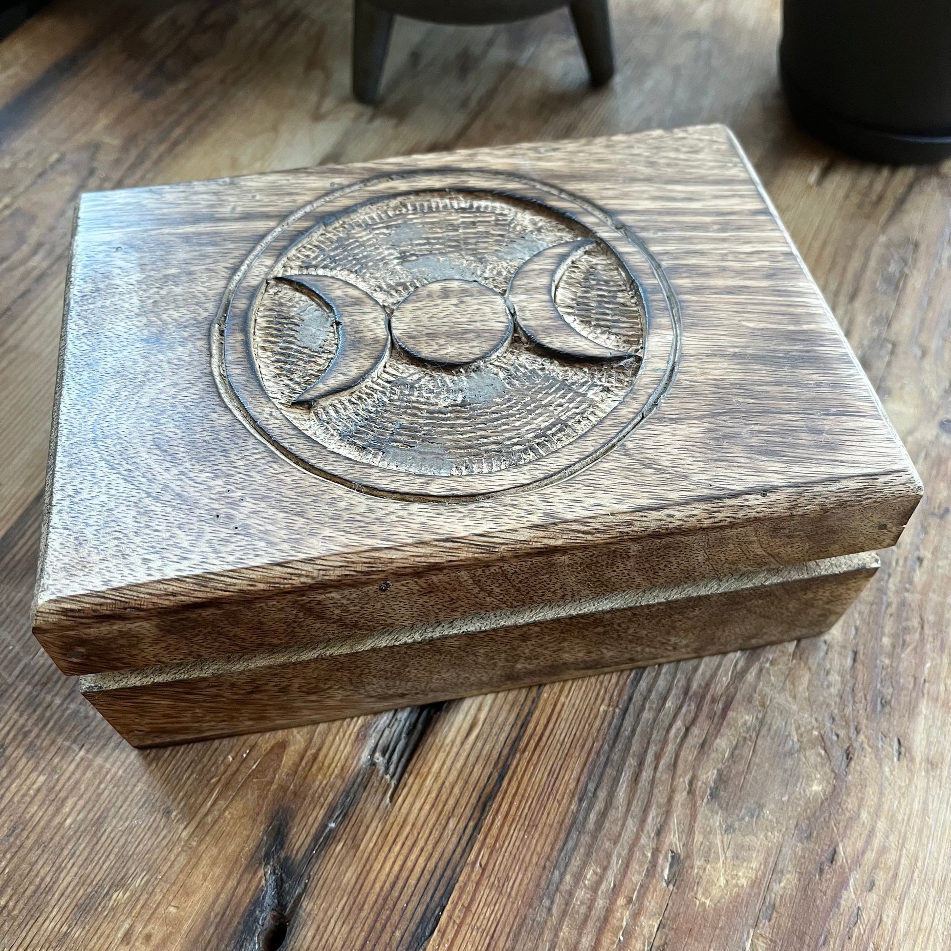 Wooden box with engraved Triple moon symbol on a wooden surface