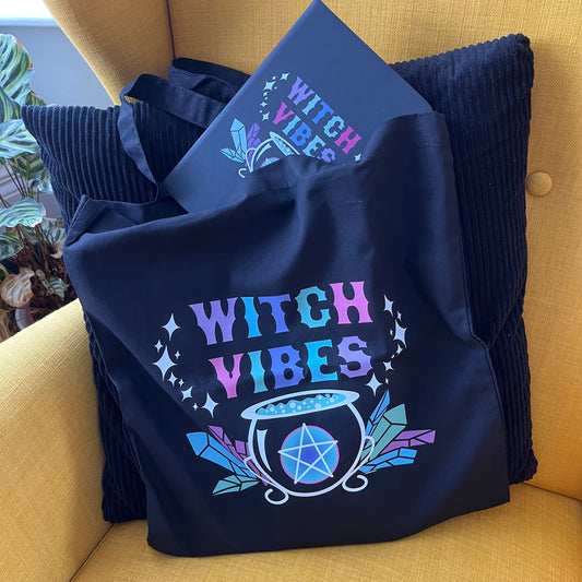 Black tote bag with 'Witch Vibes' design on a yellow couch