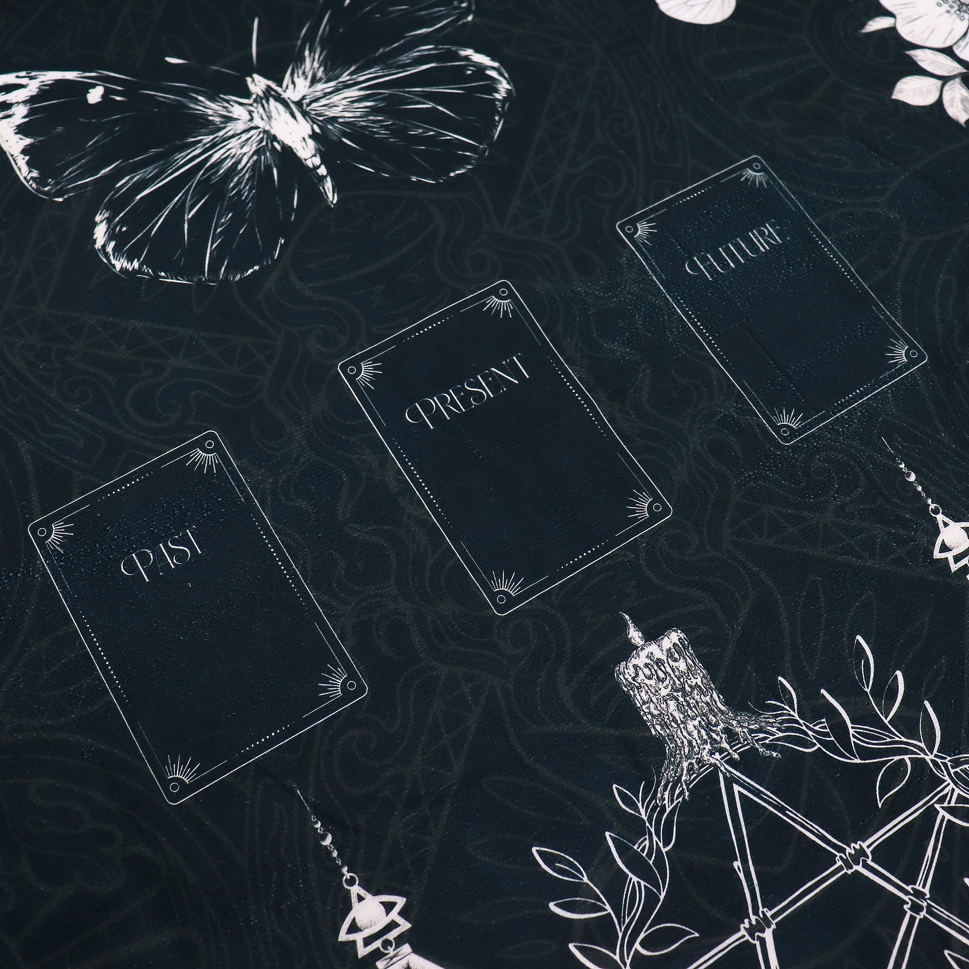 Decorative Tarot reading cloth with text 'PAST', 'PRESENT', 'FUTURE' and white butterfly on a dark background.