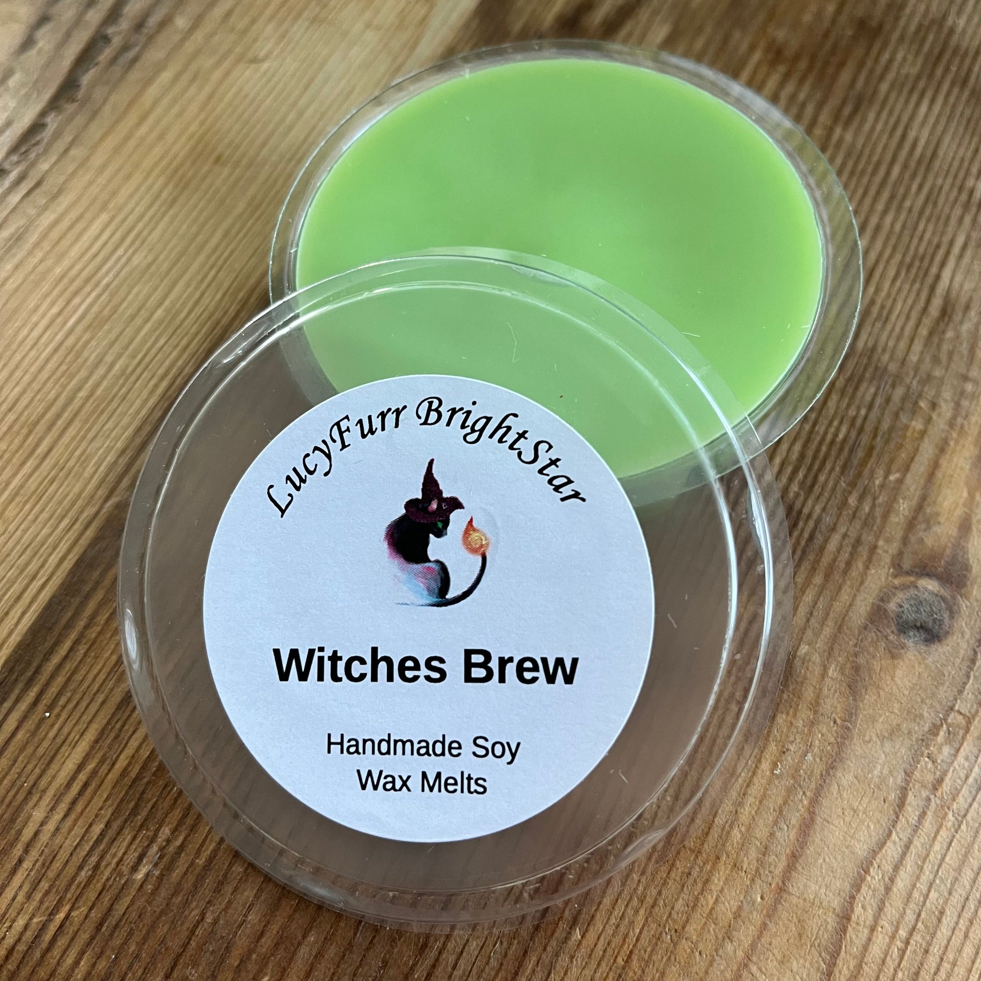 Green wax melts in a container with a label which reads Witches Brew on a wooden surface