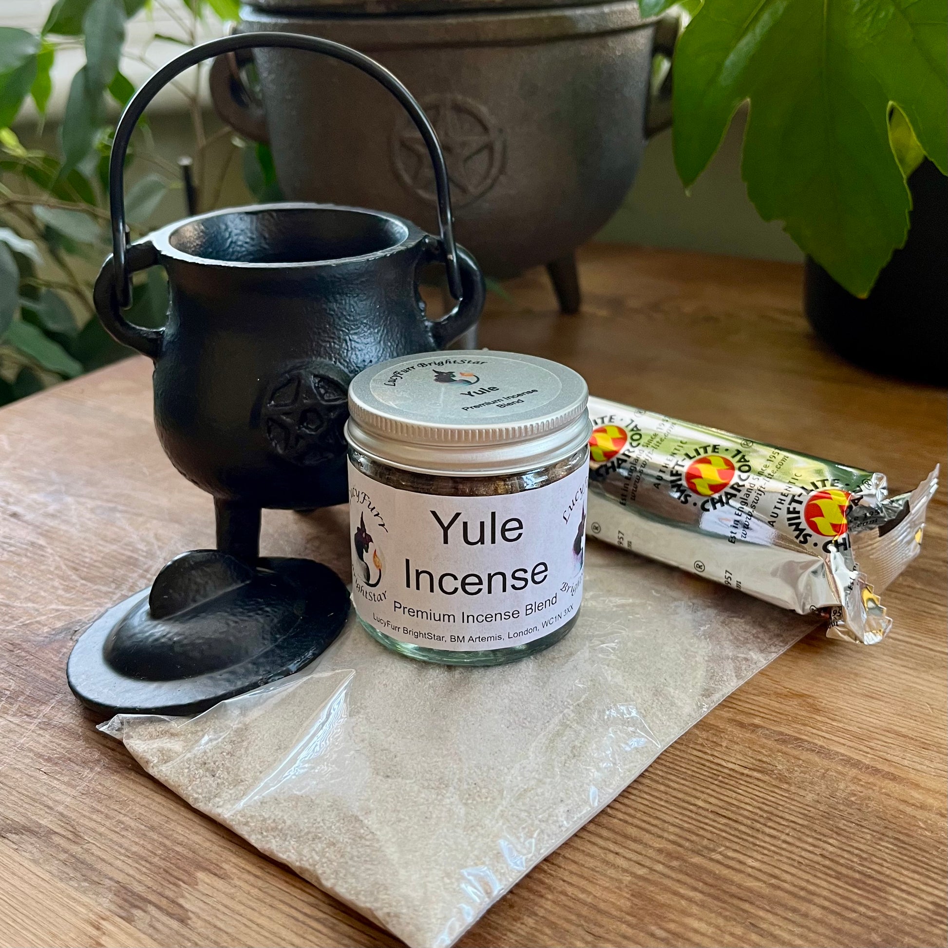 Yule incense jar with a black cauldron on a wooden surface