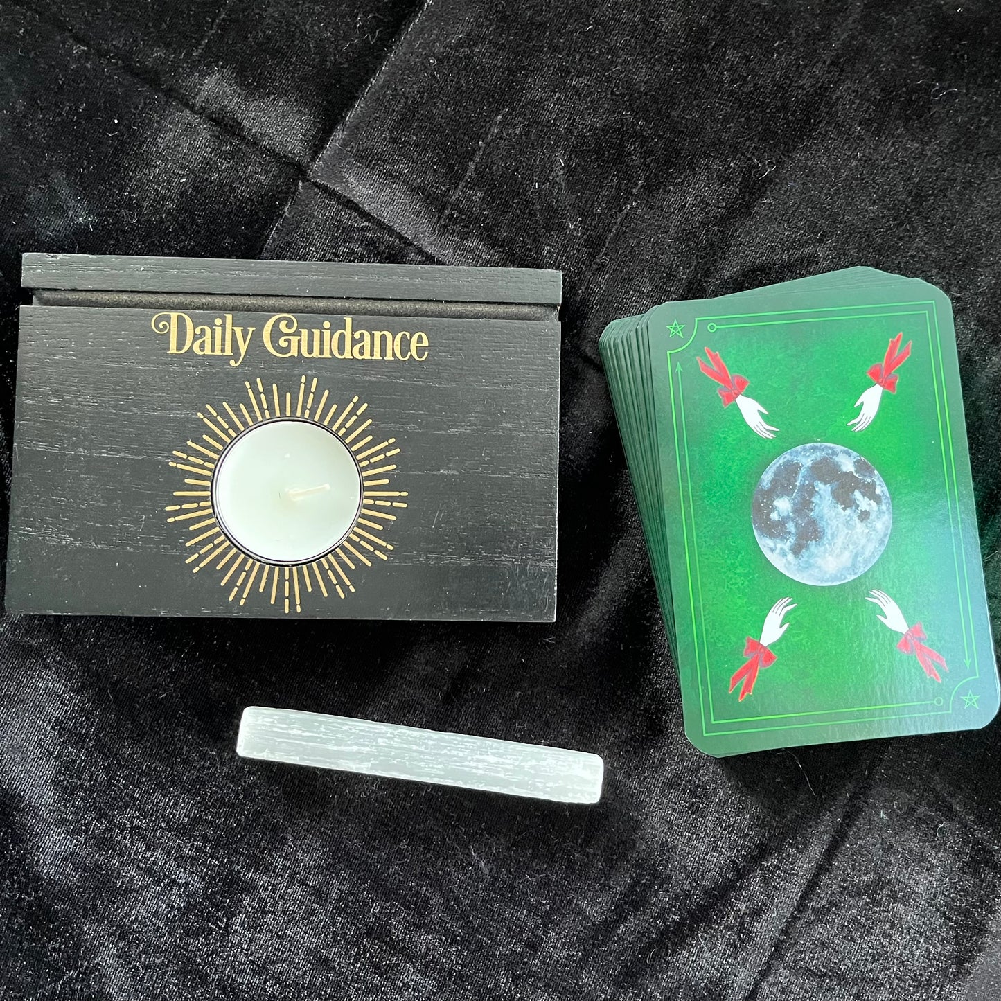 Set of tarot cards with a green card featuring a moon design on a black textured surface.