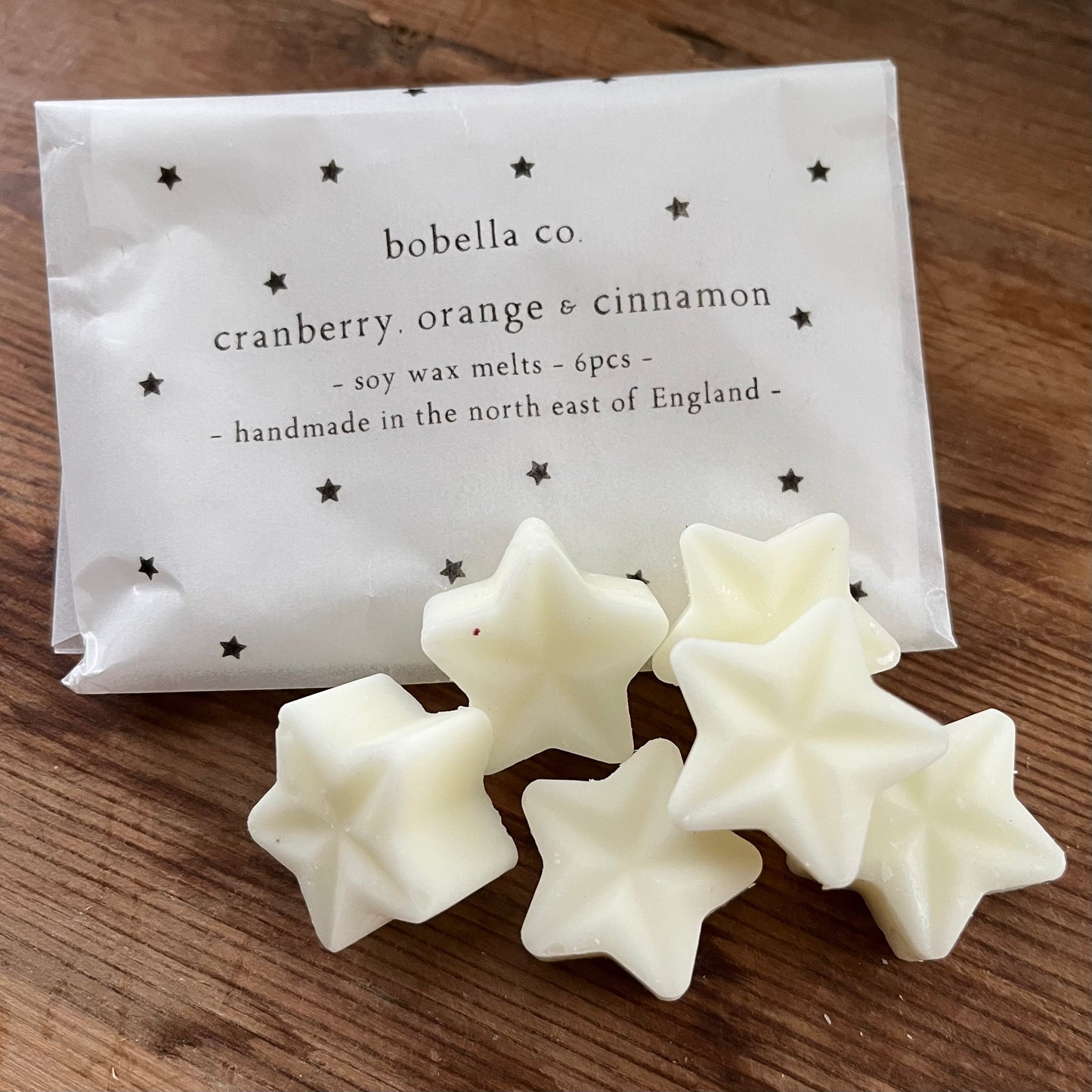 Christmas scented Star-shaped wax melts with packaging labeled 'bobella co.' on a wooden surface
