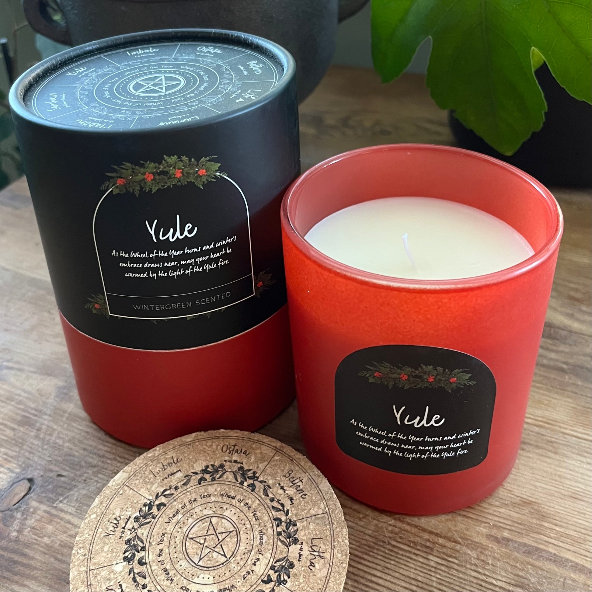 Candle with black lid and red container on a wooden surface