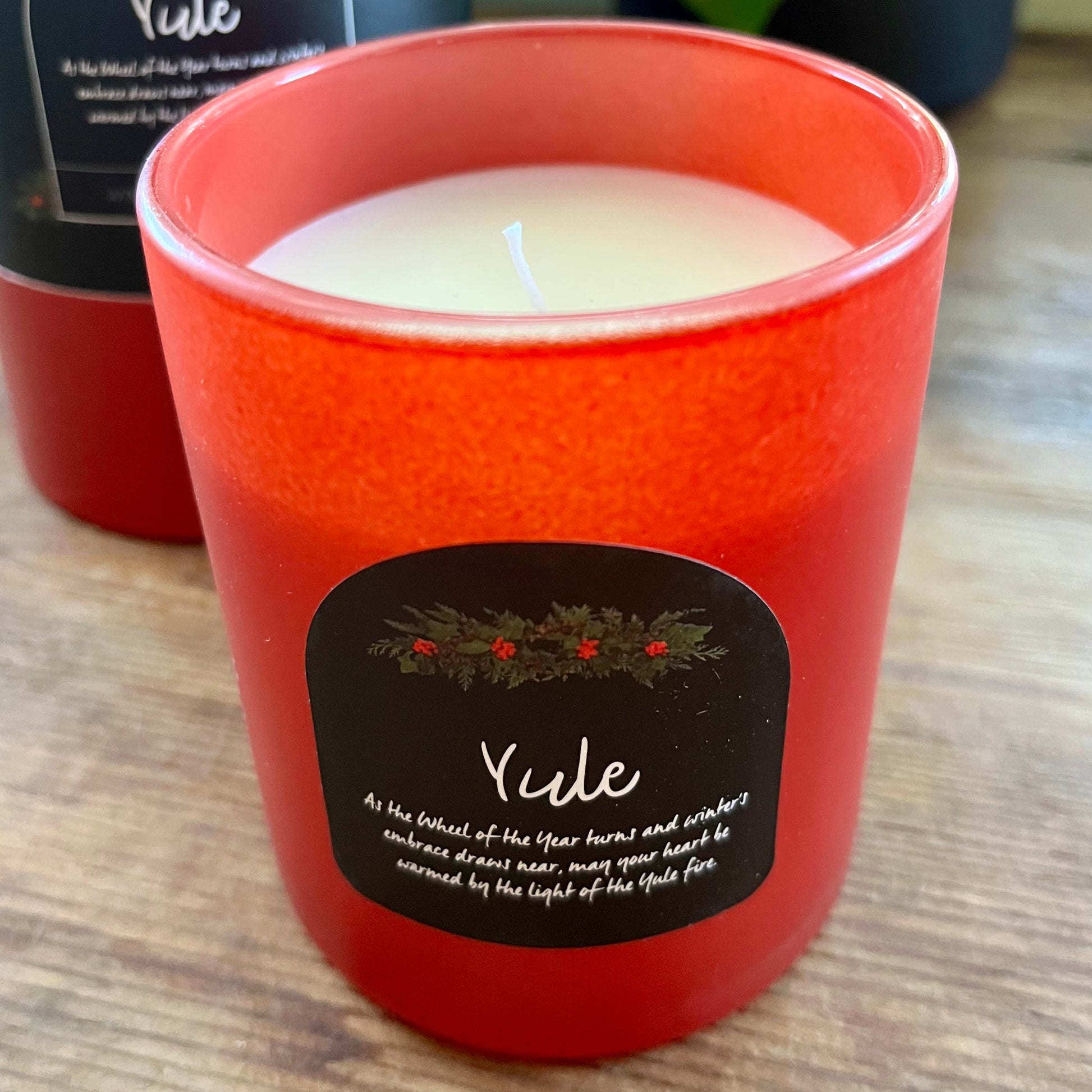Red candle with a 'Yule' label on a wooden surface