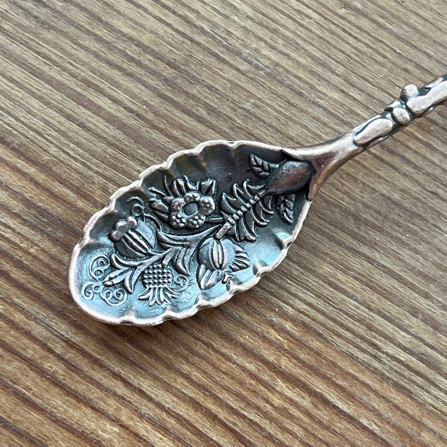 Decorative Bronze spoon with floral patterns on a wooden surface