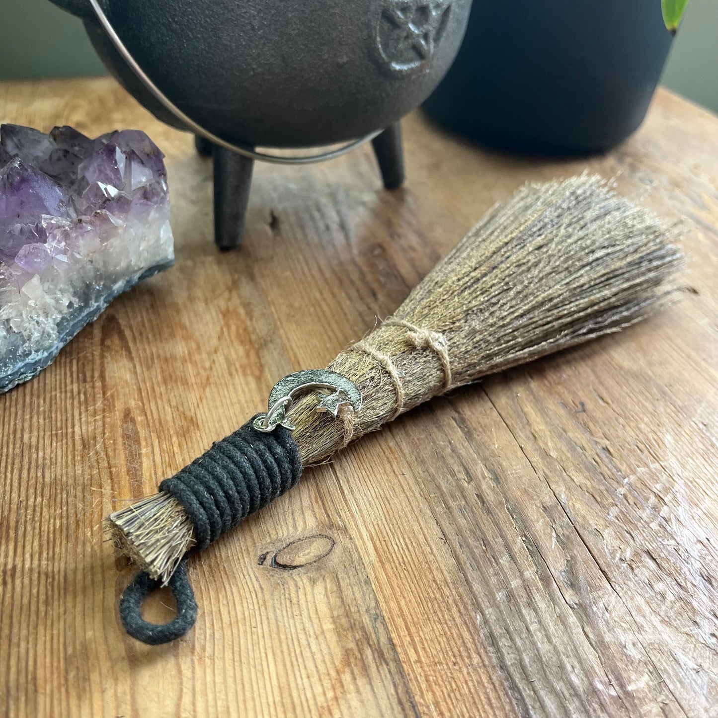 Broom with a pentagram design on a wooden surface next to crystals