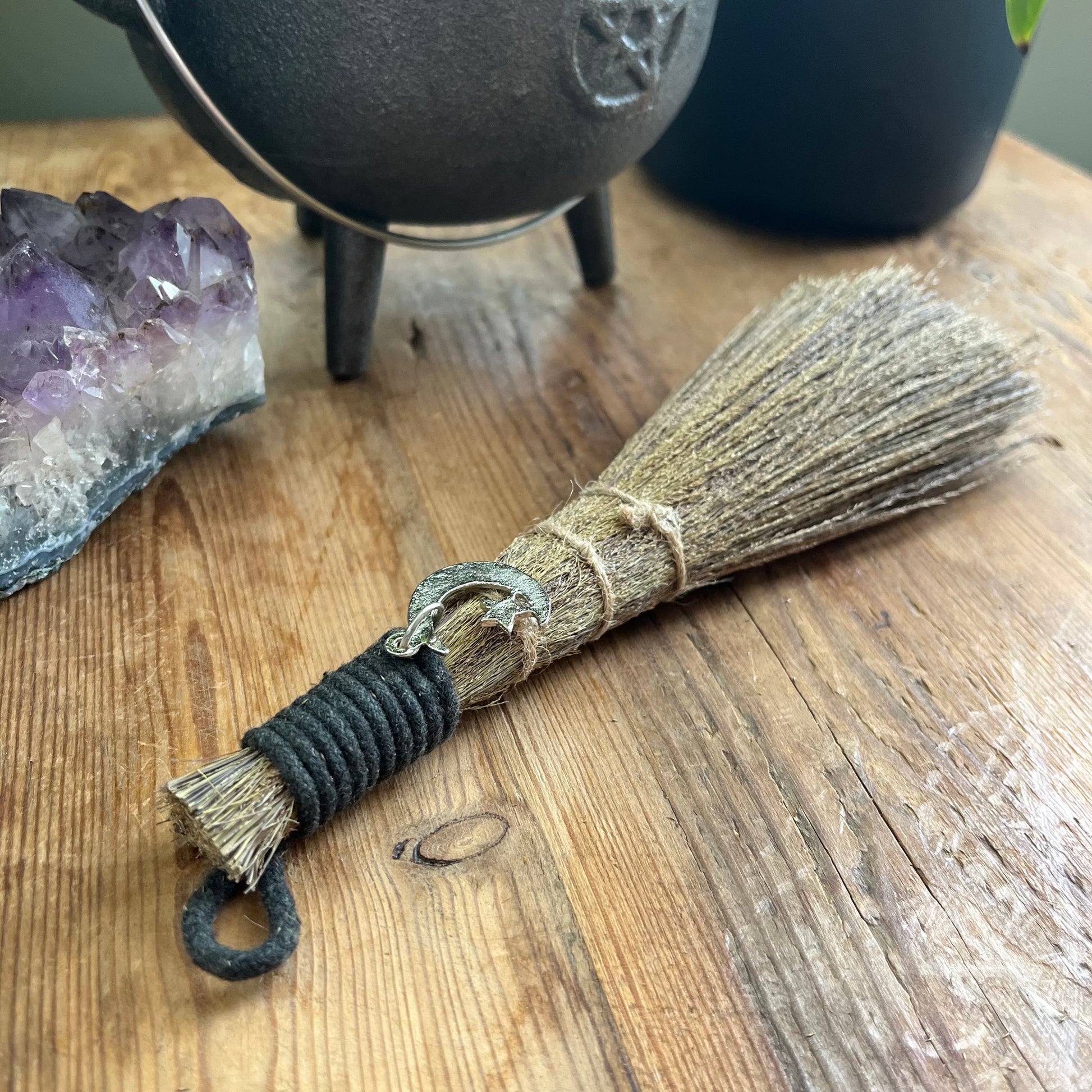 Broom with a pentagram design on a wooden surface next to crystals