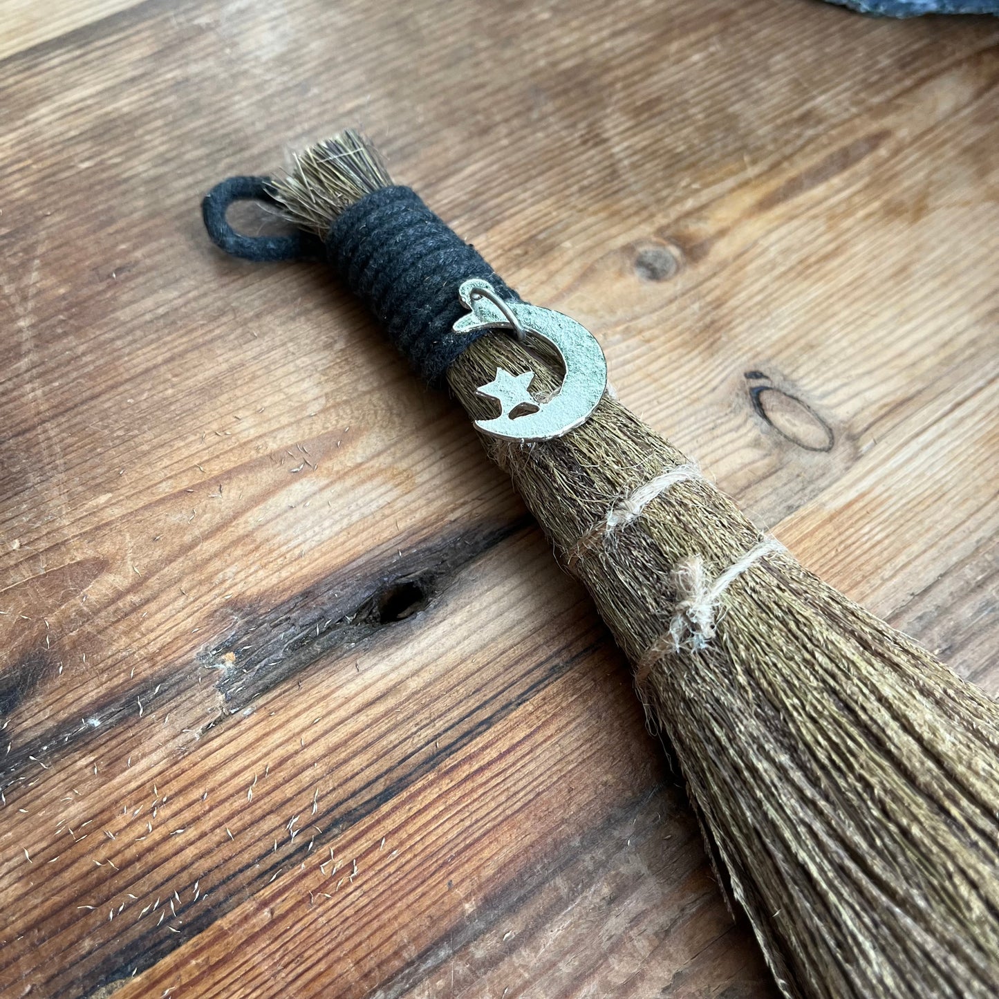 Broom with a decorative hook featuring a star and moon on a wooden surface