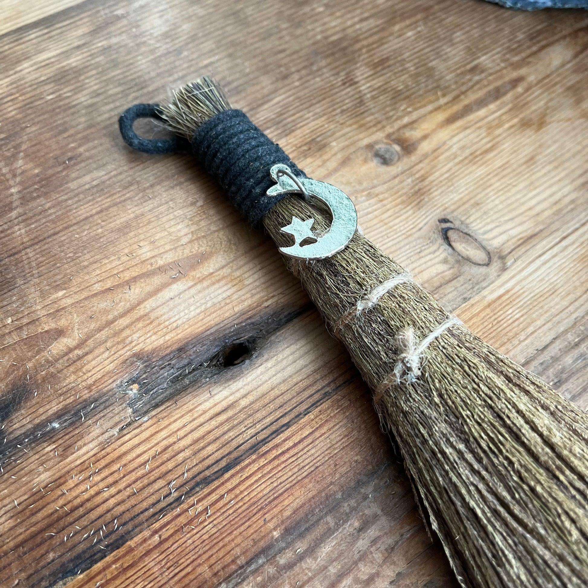 Broom with a decorative hook featuring a star and moon on a wooden surface