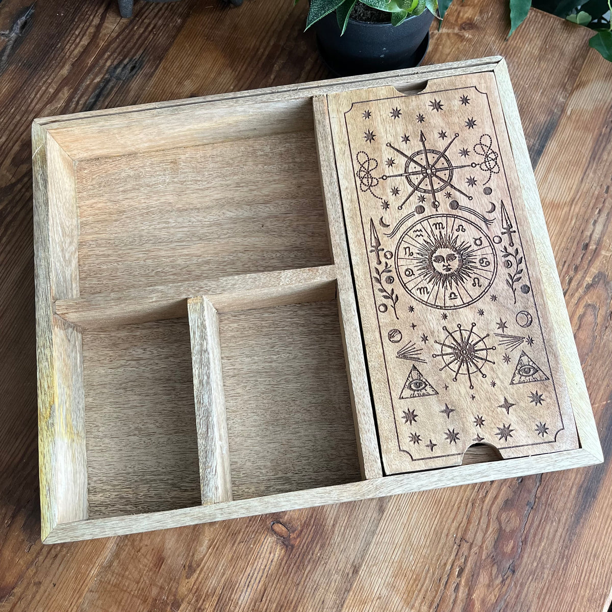 A rectangular wooden organizer box with three compartments and a lid decorated with engraved celestial symbols, shown on a wooden tabletop.