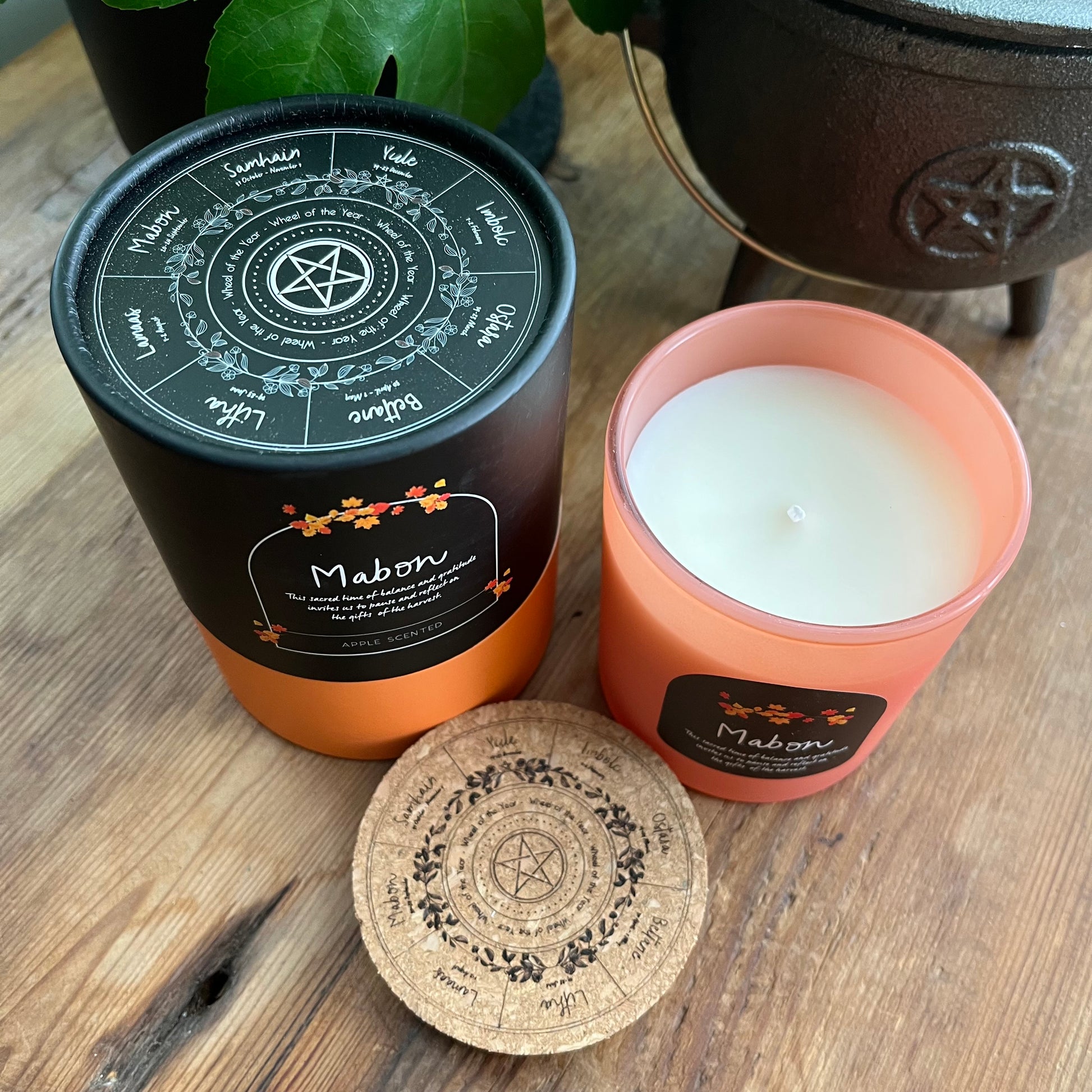 Candle with decorative wheel of the year label on a wooden surface