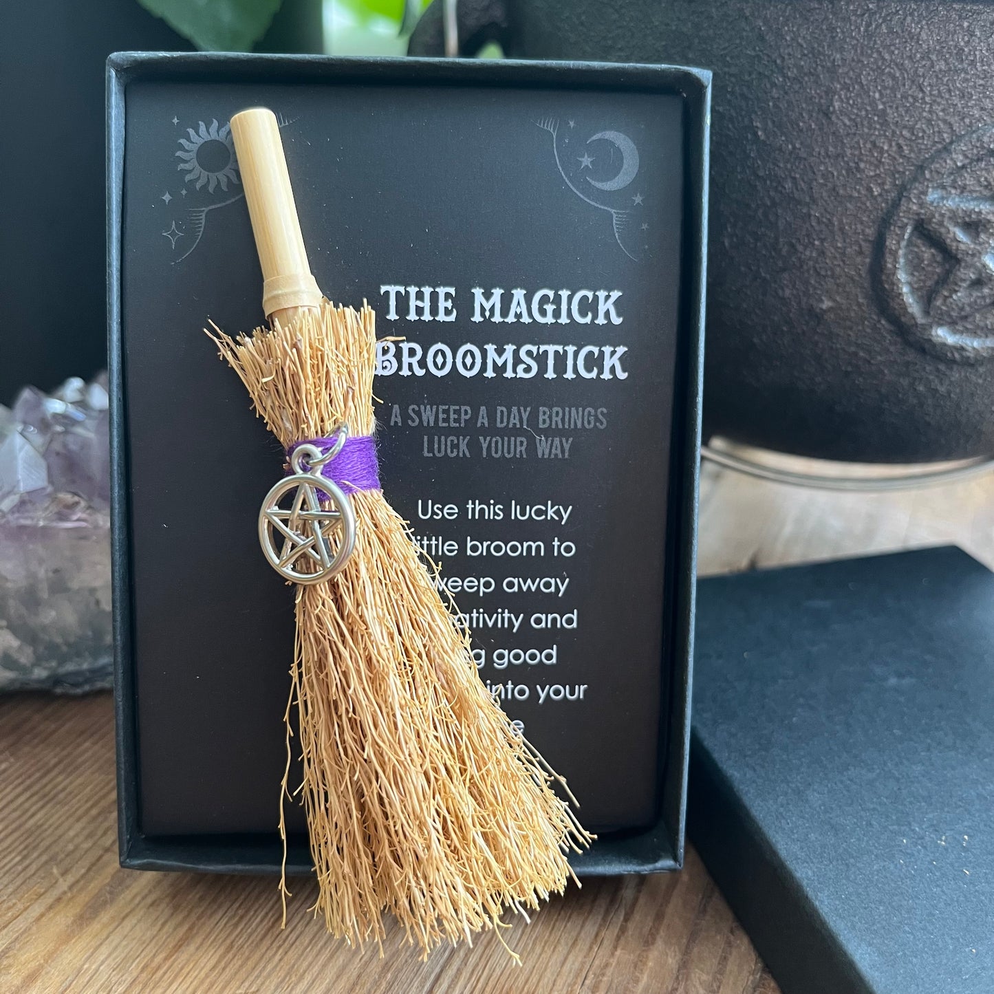 Magick broomstick with pentacle charm in front of a black box with text