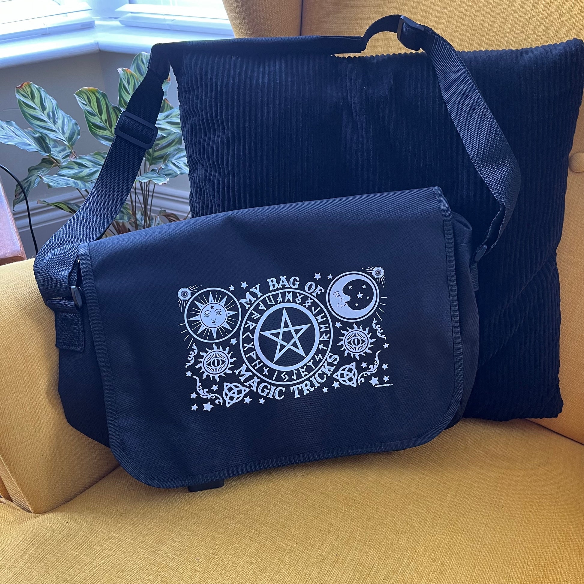 Black bag with white mystical symbol designs and text on a yellow couch