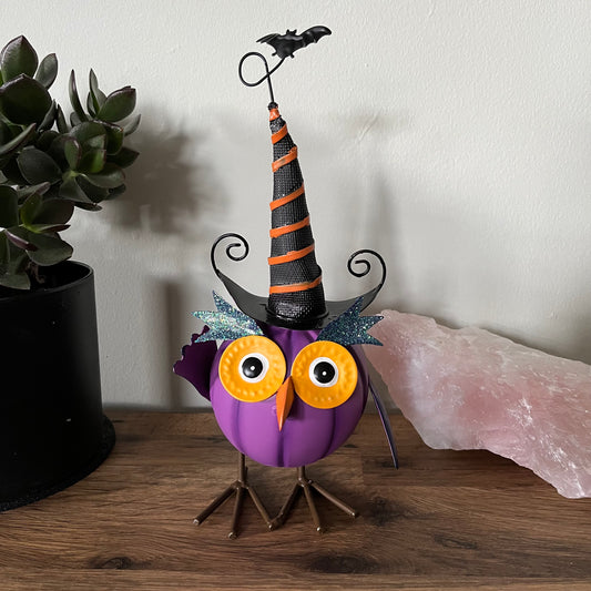 Halloween-themed owl decoration with a witch hat on a wooden surface.