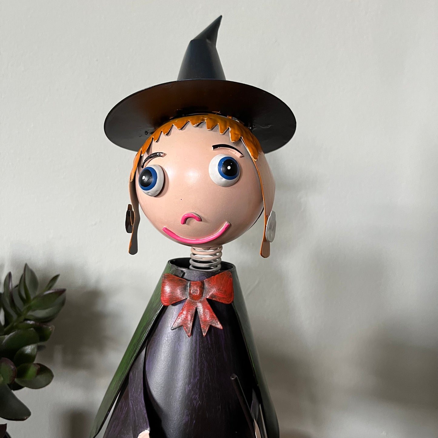 Toy figure of a witch with a surprised expression on a plain background