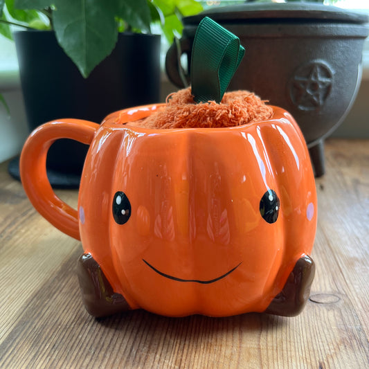 Pumpkin-shaped mug with a face on a wooden surface