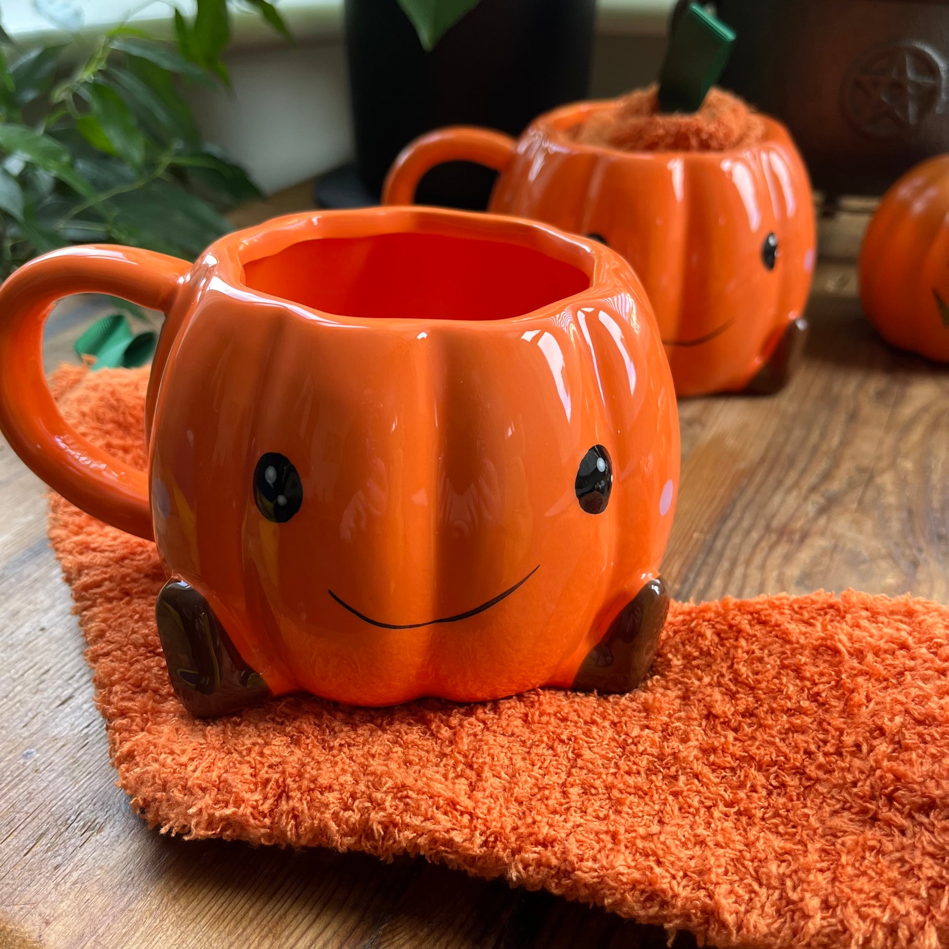 Pumpkin-shaped mugs with faces on a wooden surface