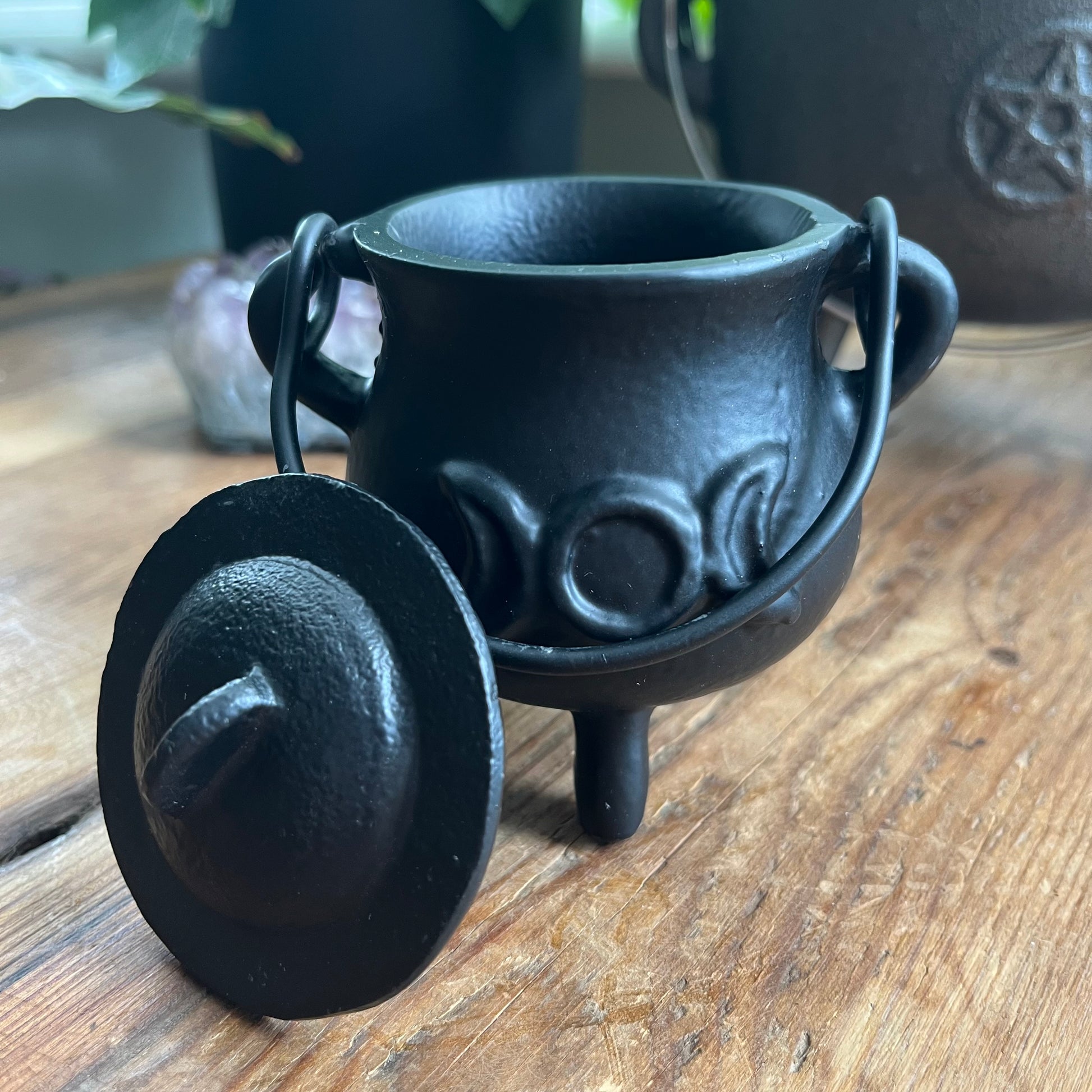 Black cast iron cauldron with lid on a wooden surface