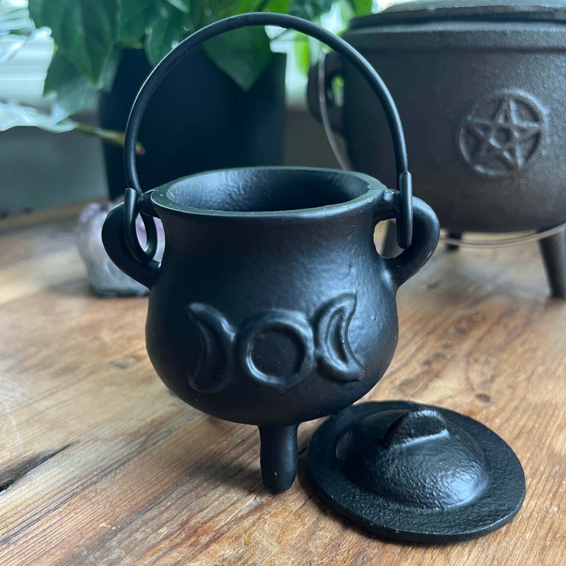 Black cast iron cauldron with lid on a wooden surface
