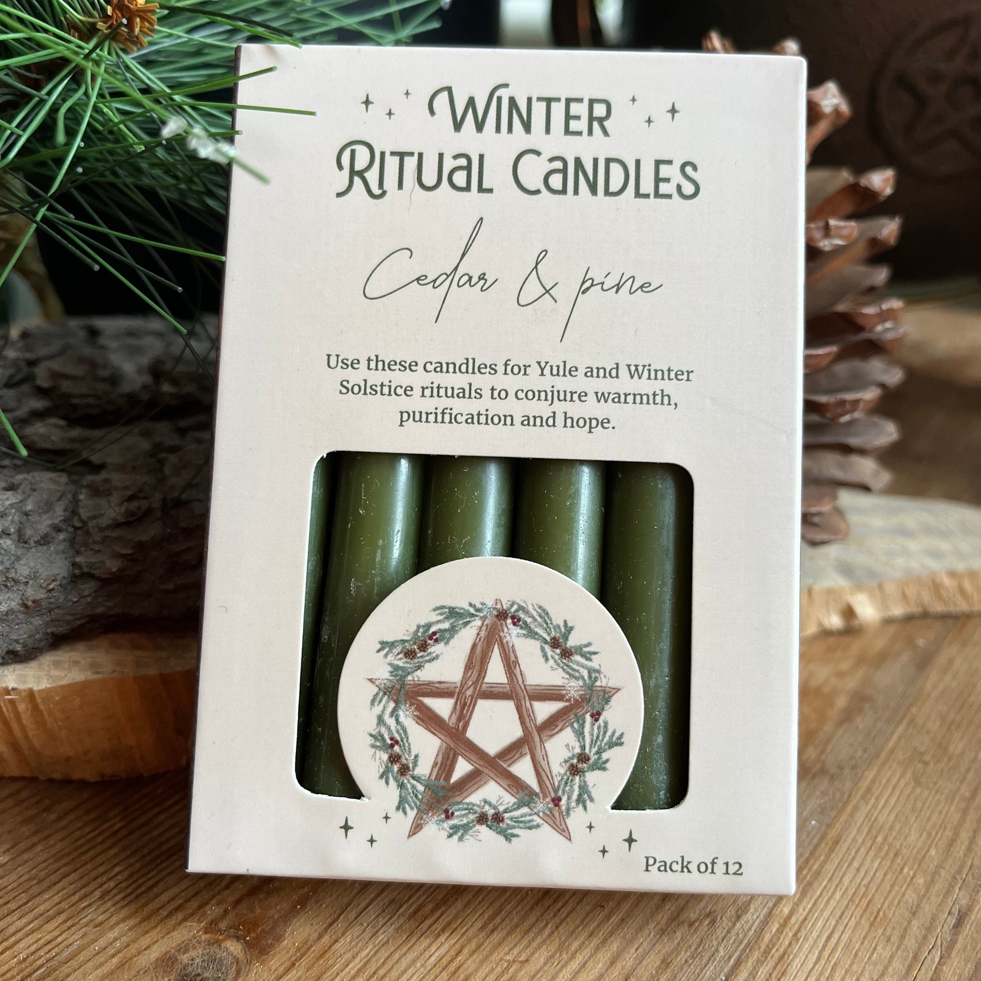 A set of 12 green spell cnadles in a cream coloured box adorned with a pentagram and a holly wreath. 