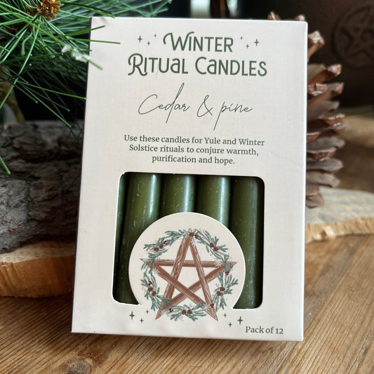 A set of 12 green spell cnadles in a cream coloured box adorned with a pentagram and a holly wreath. 