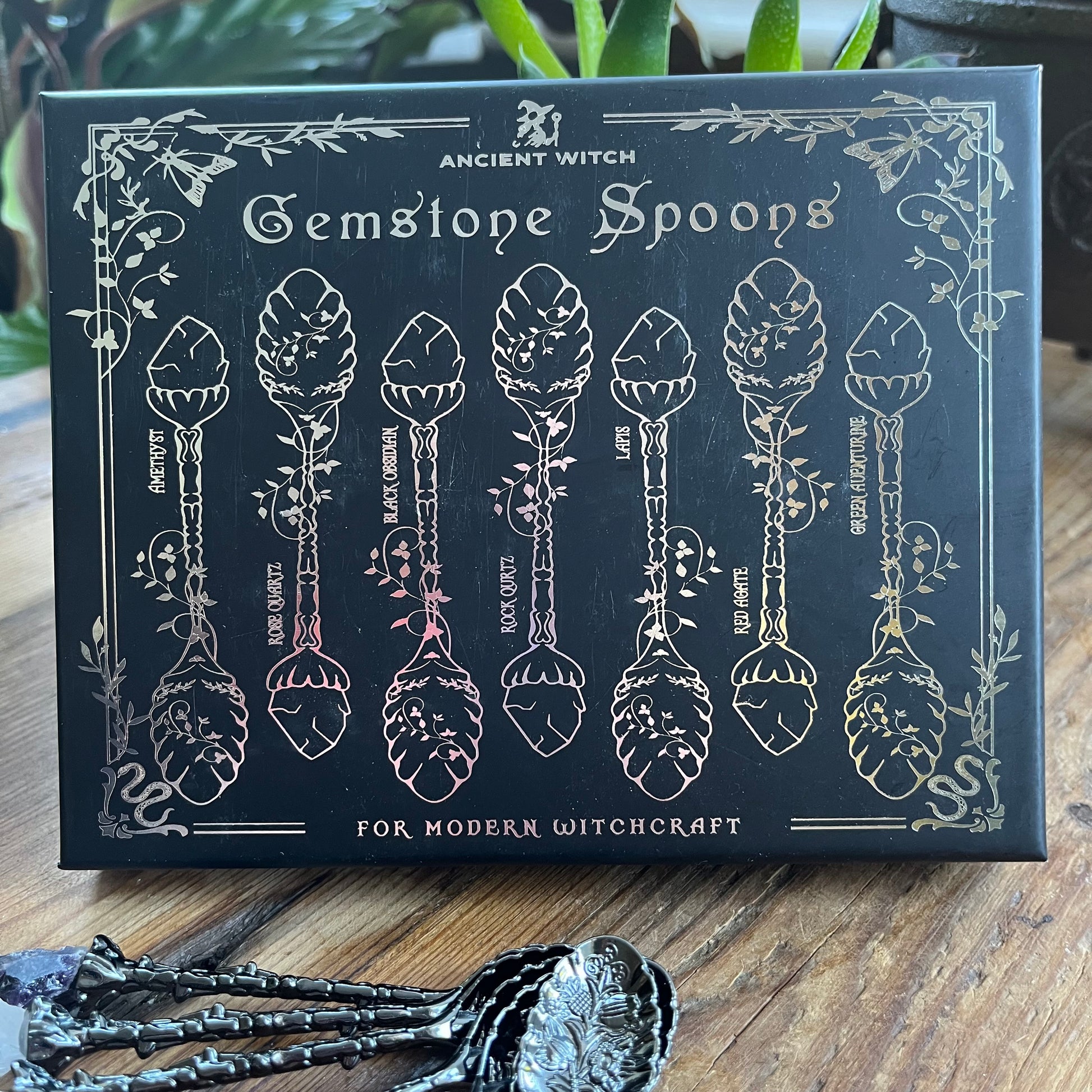 Box of Gemstone Spoons for Modern Witchcraft with engraved designs on a wooden surface.